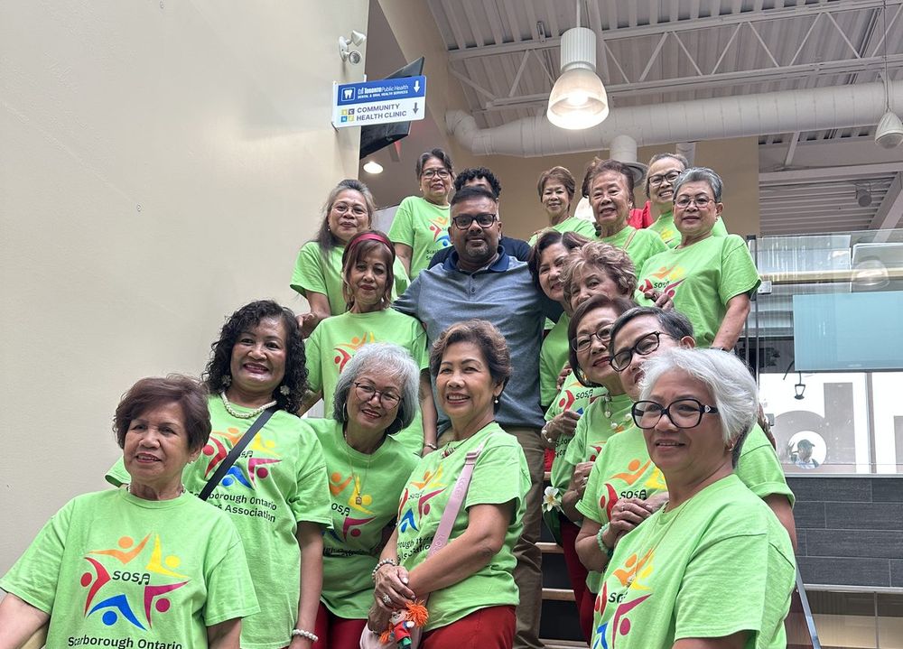 Ahsanul Hafiz with a Filipino seniors group in matching green shirts on the steps of a community centre